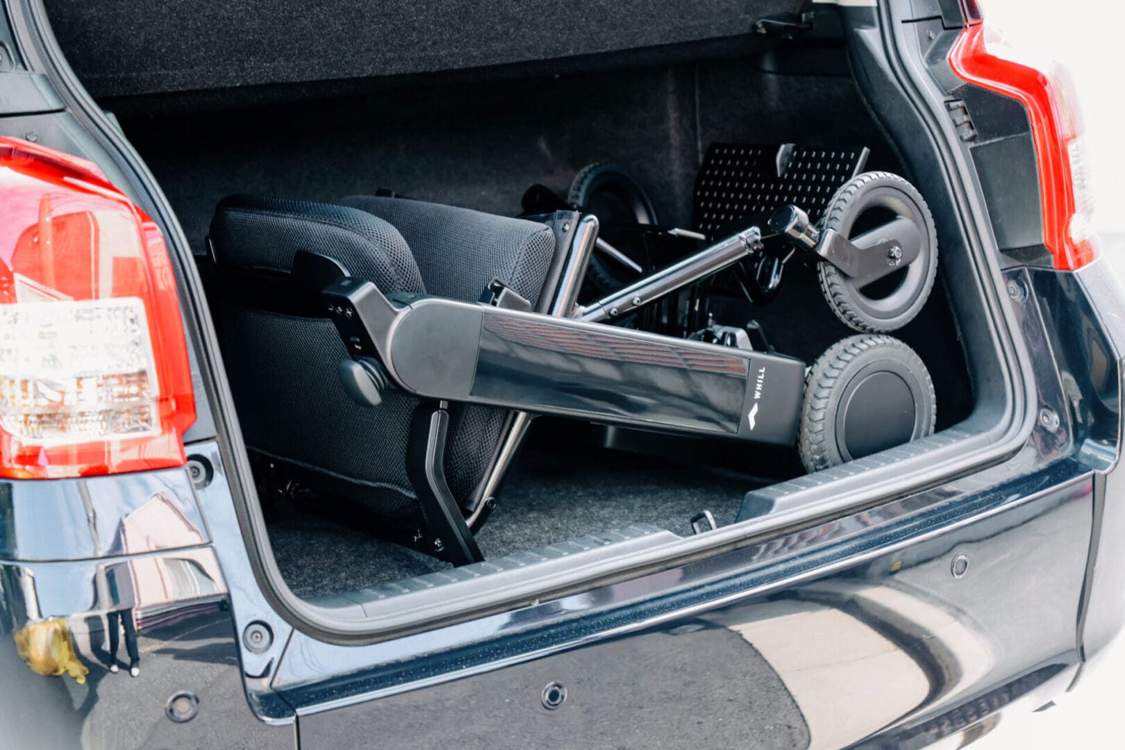 The trunk of a car with a wheelchair in it.