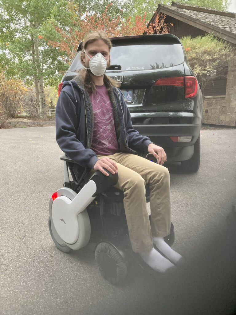 A man wearing a mask sitting on an electric wheel chair