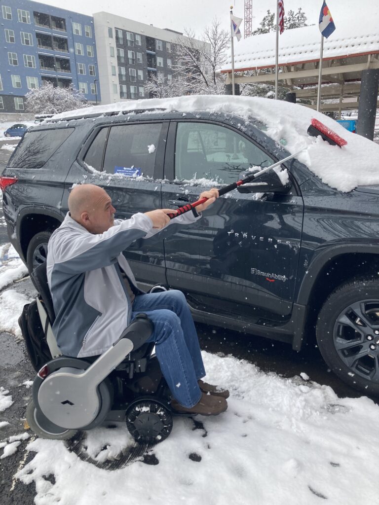 A paralyzed man cleaning snow from his car