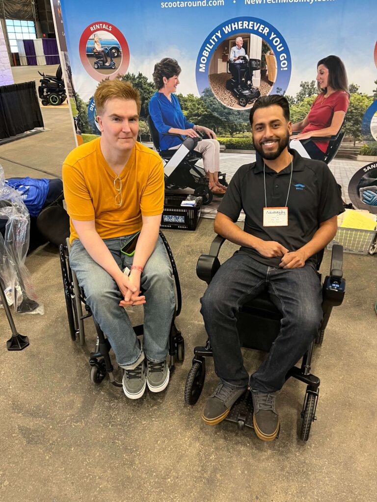 Two men sitting on the wheel chair and smiling