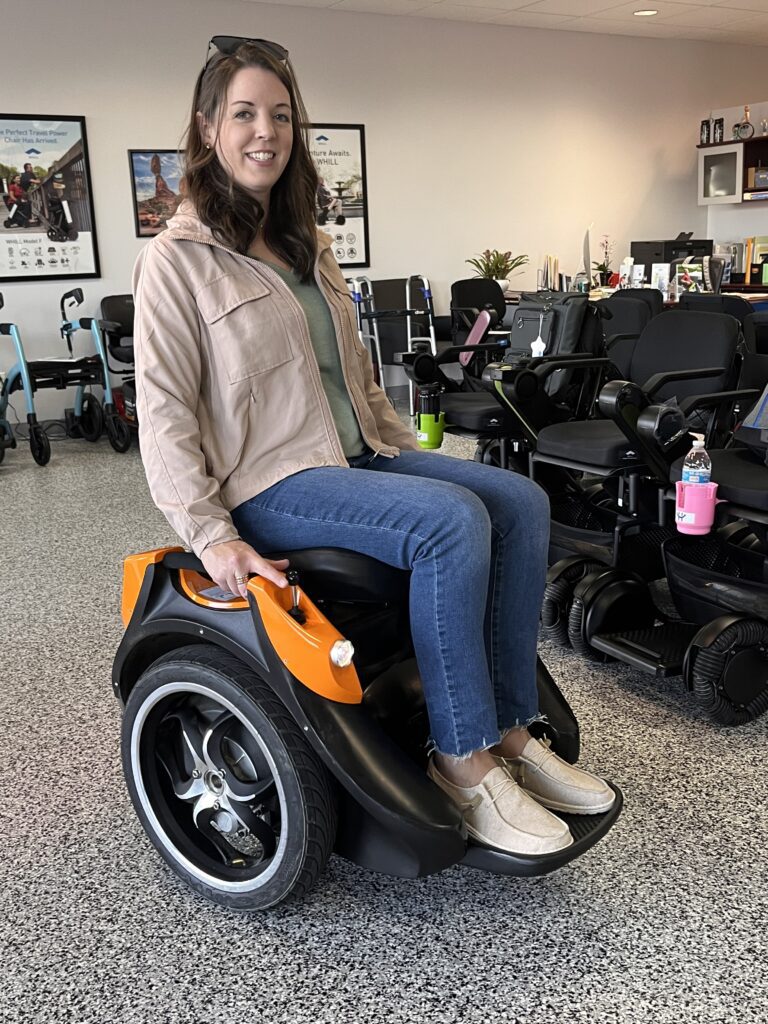 A woman with brown hair using the WHILL Mobility Device