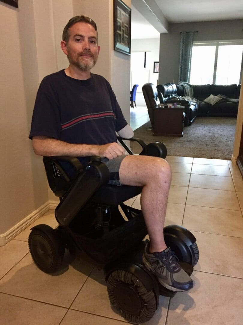 A man sitting on a wheel chair in a living room.