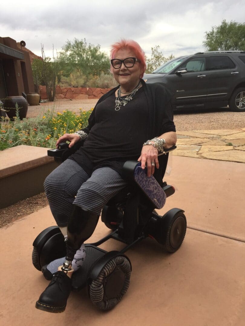 A woman in a wheelchair sitting on a sidewalk.