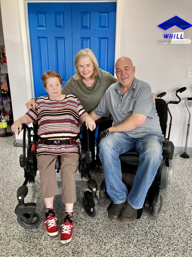 A man and woman posing for a photo in a wheelchair.