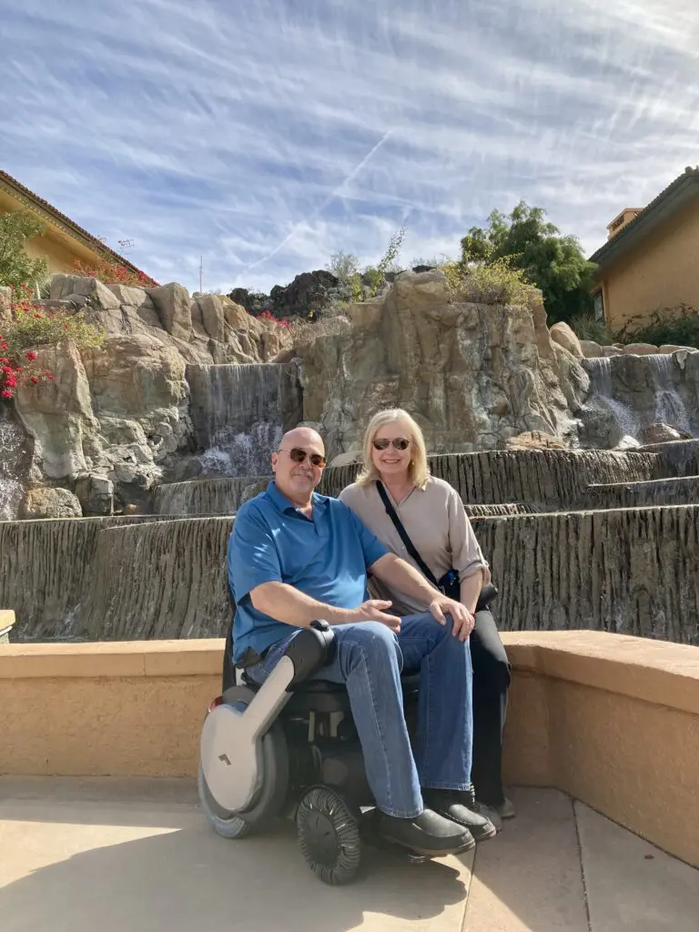 A couple in a wheelchair in front of a waterfall.