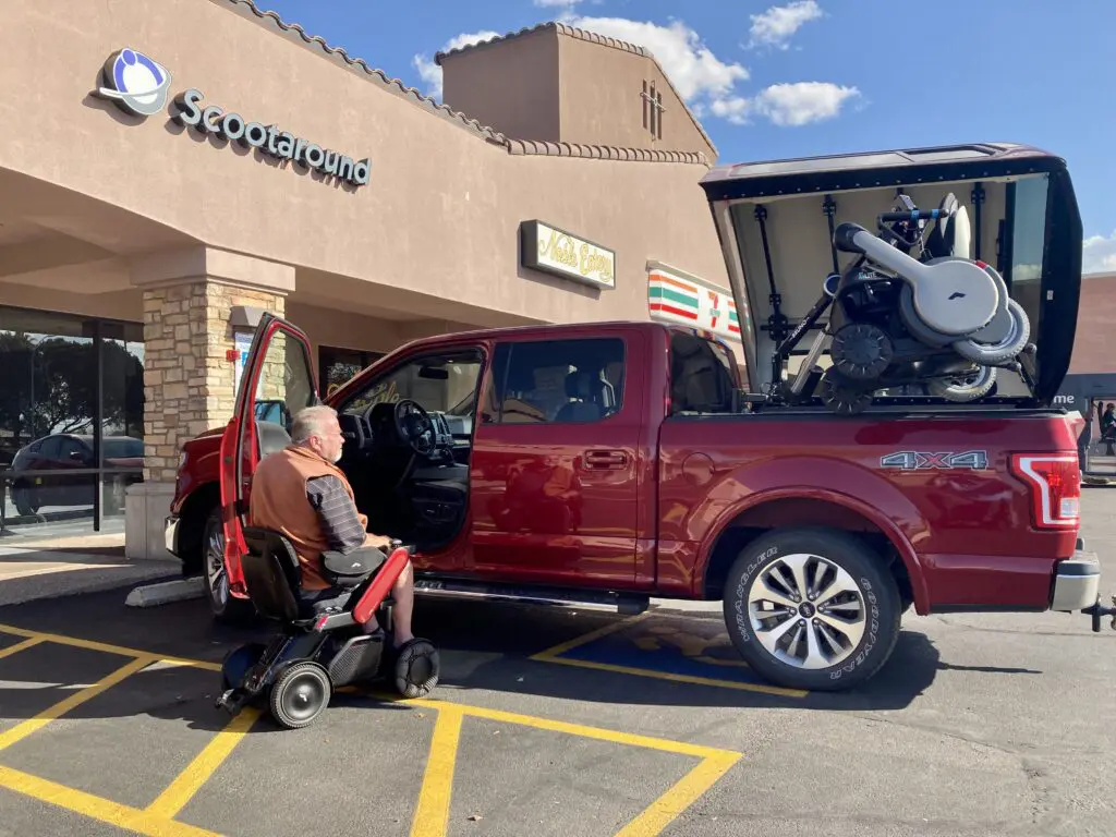 A man in a wheelchair is parked in front of a truck.