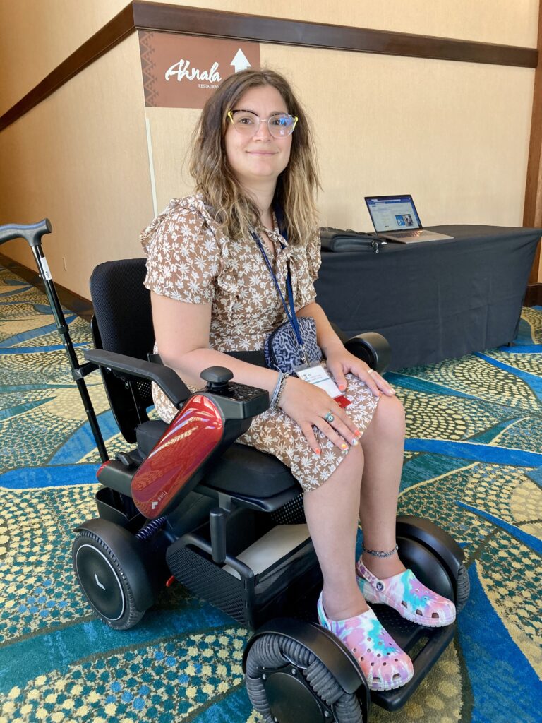 A woman sitting in a wheel chair at a conference.