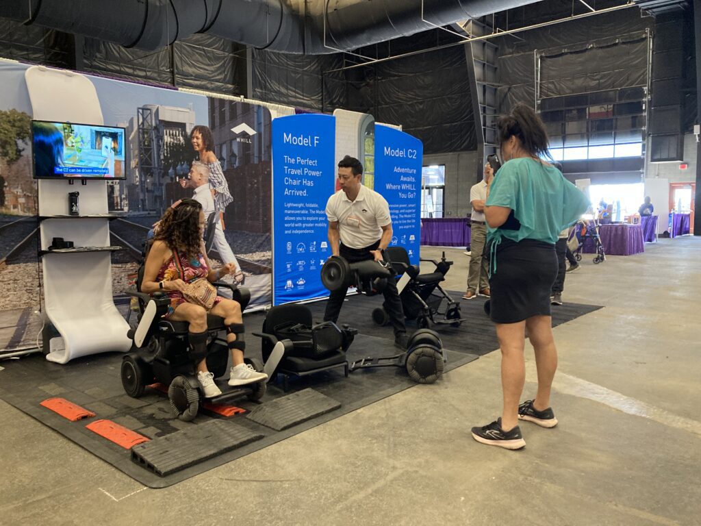 A group of people standing in front of a booth with a person in a wheelchair.