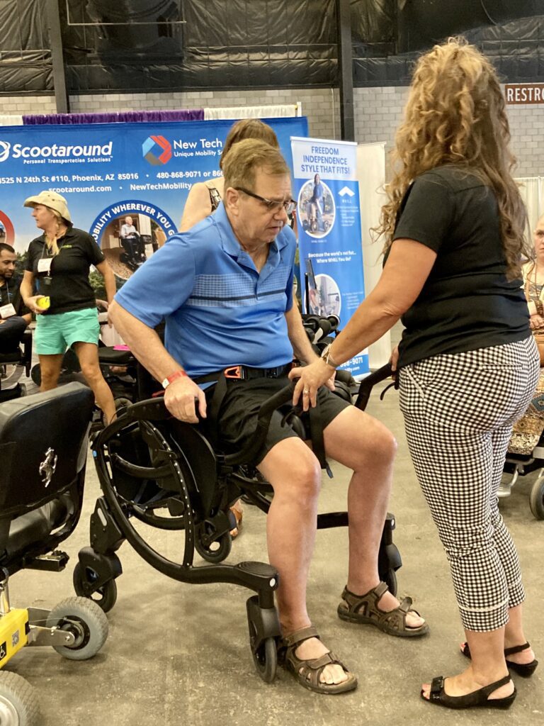 A woman in a wheelchair talking to a man in a wheelchair.