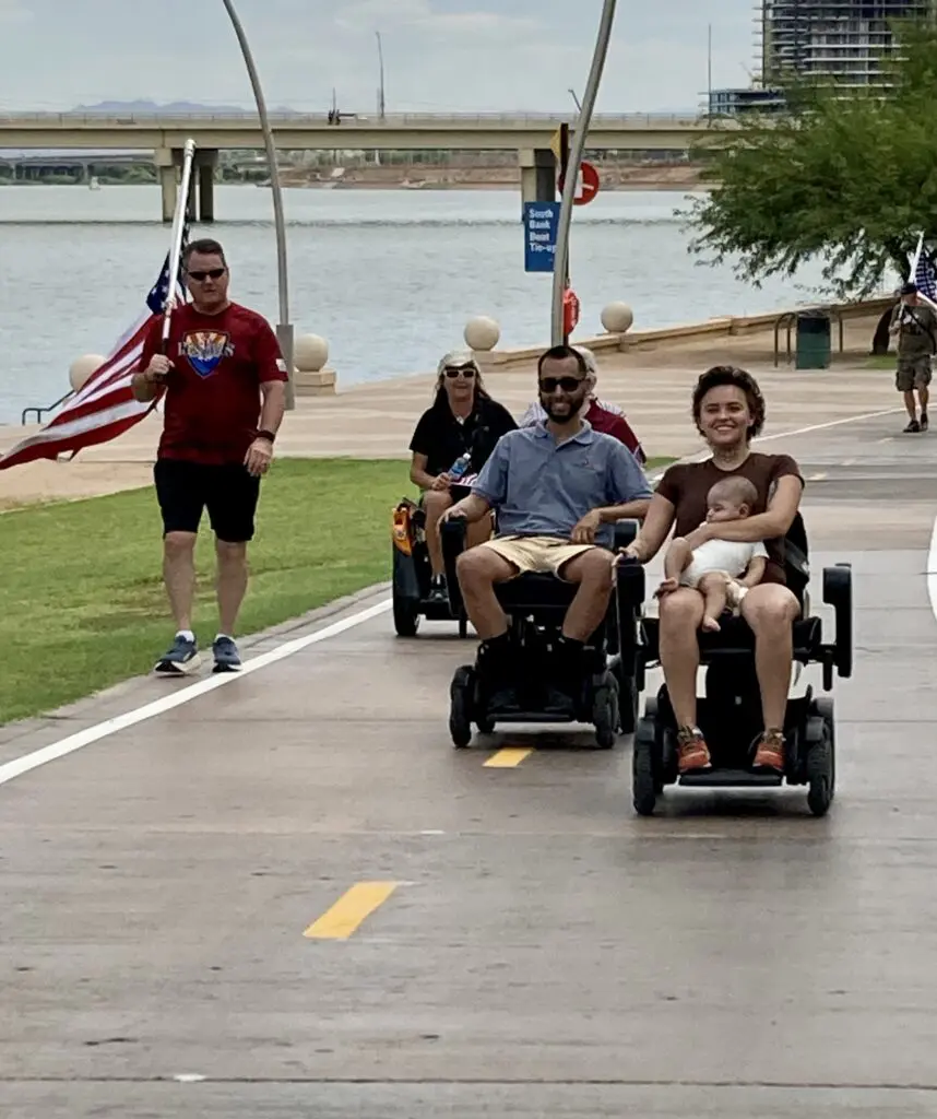 A group of people riding in wheelchairs on a sidewalk.