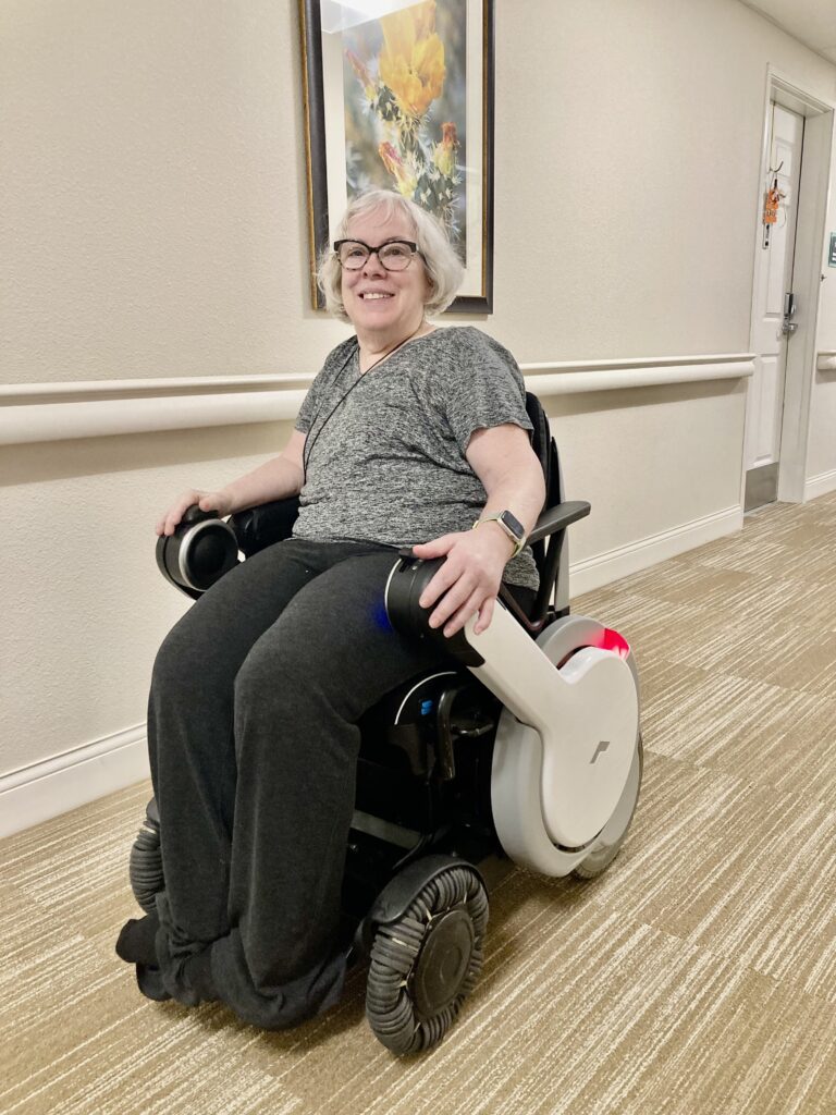 A woman sitting in a wheel chair in a hallway.