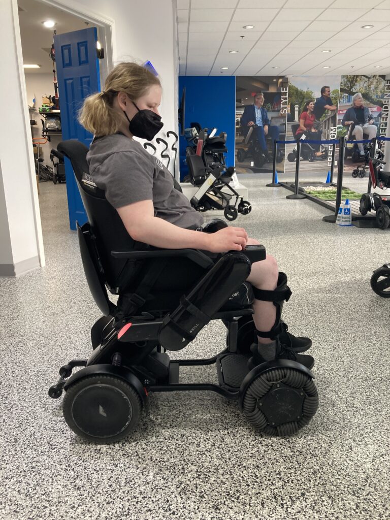 A woman sitting in a wheelchair in a gym.