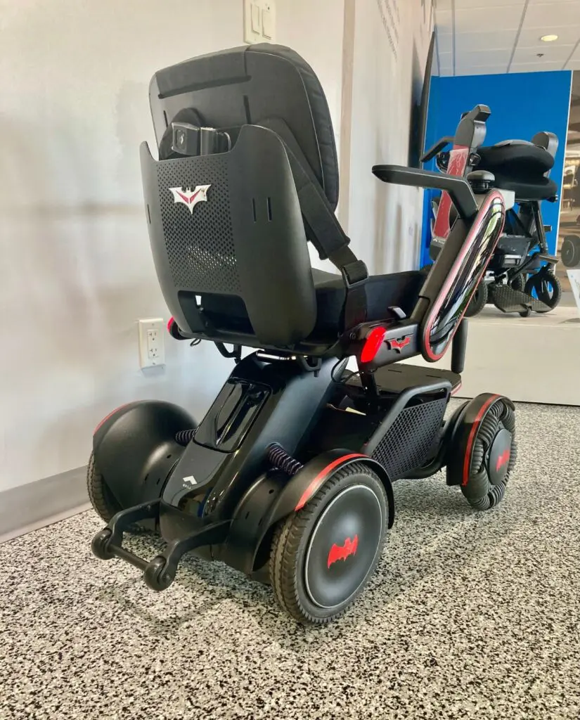 A black and red wheeled scooter is parked in a showroom.