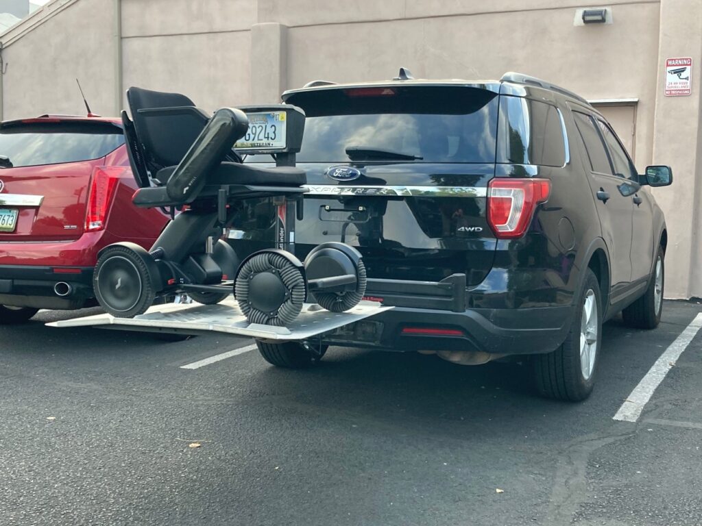 A suv parked in a parking lot with a wheelchair attached to it.