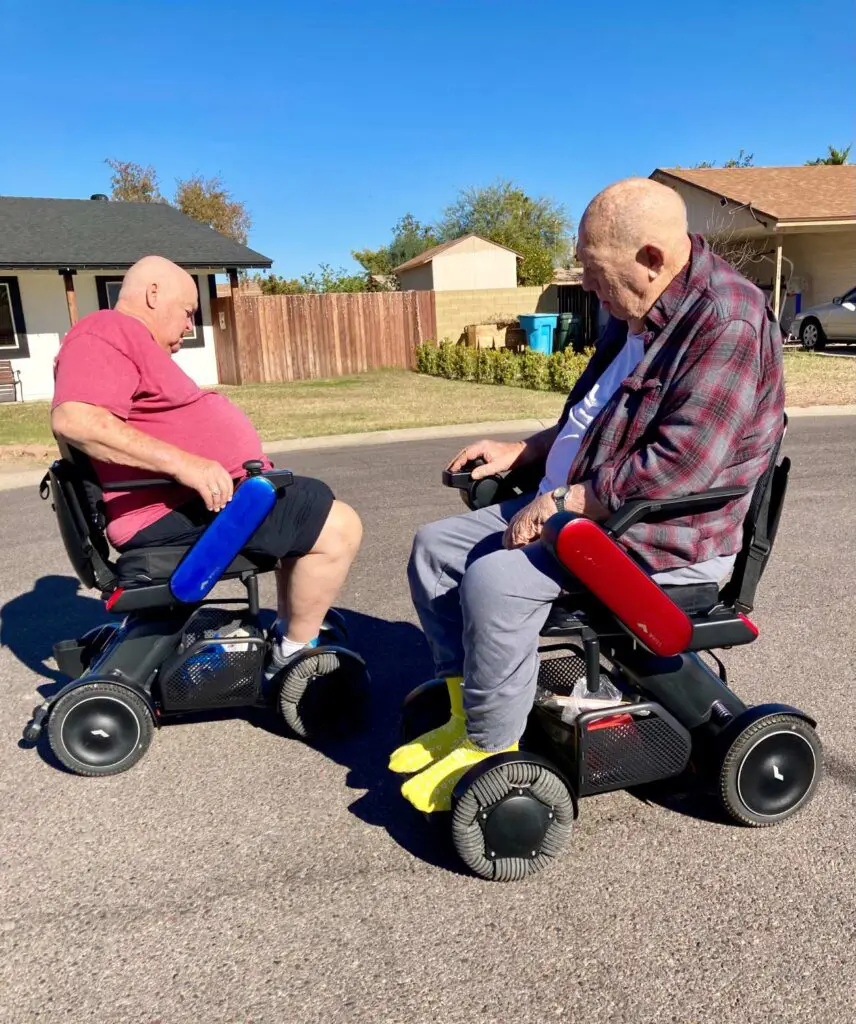 Two elderly men sitting on a pair of electric scooters.