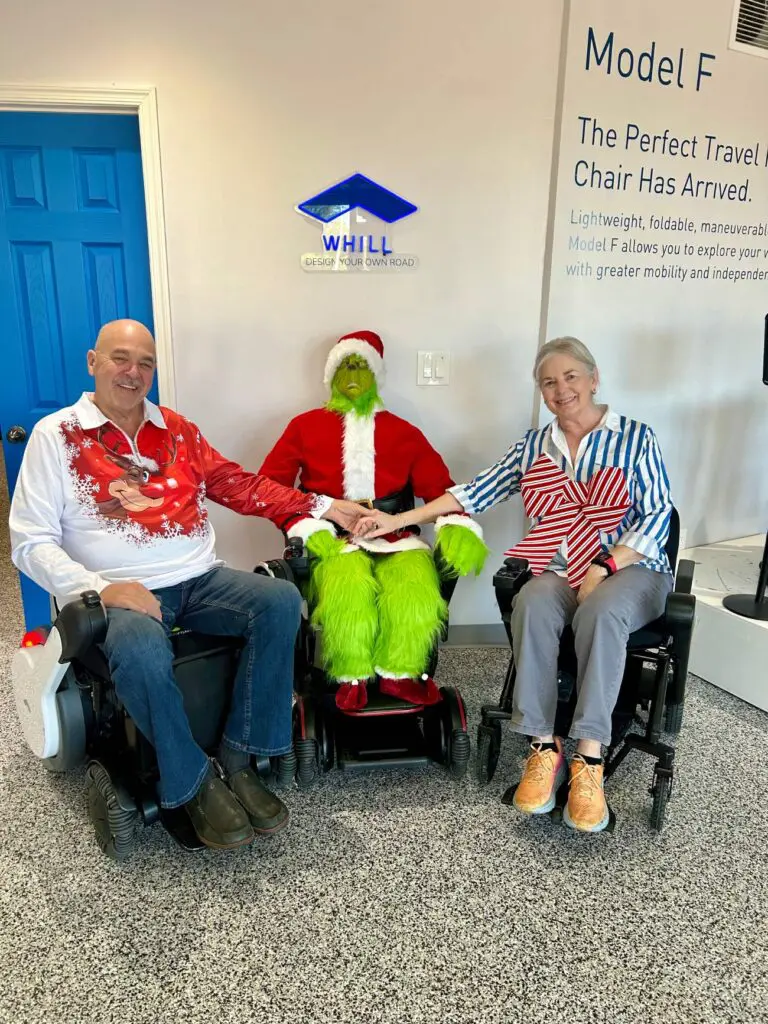 Two people in wheelchairs with a santa claus.