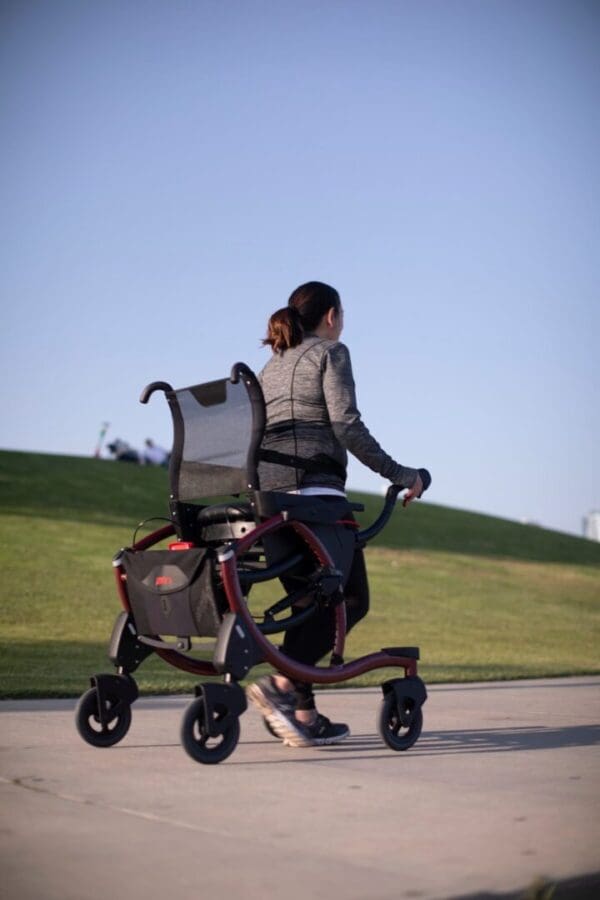 A woman is riding a walker in a park.