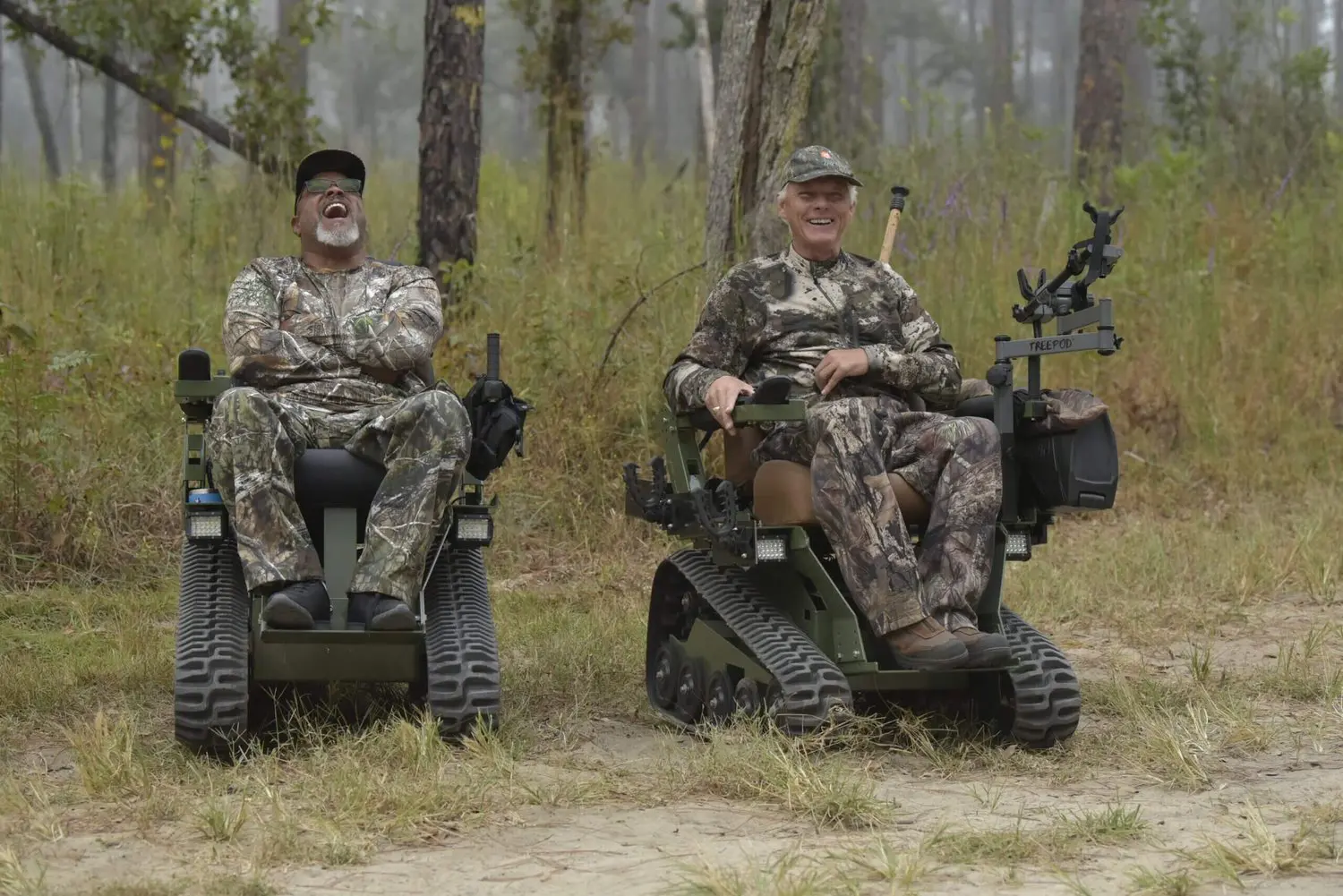 Two men in camouflage gear sitting on a motorized vehicle.